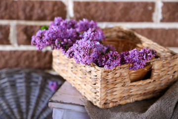 Obraz na płótnie Canvas Beautiful lilac flowers in wicker basket,