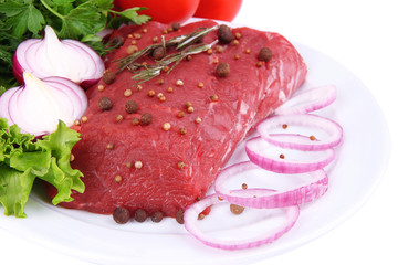 Raw beef meat with vegetables on plate close up
