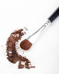 Crushed eyeshadow and professional make-up brush isolated