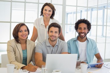 Smiling business people using laptop together at office