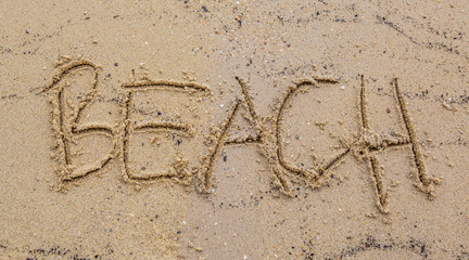 Beach with the word BEACH scribbled on the sand 