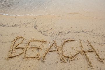 Beach with the word BEACH scribbled on the sand 
