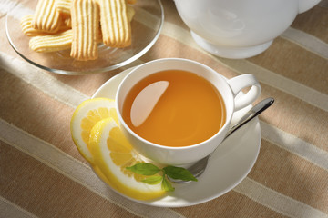 Cup of tea with lemon and cookies on table