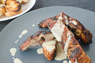 Spareribs on grill with dip and toasted baguette