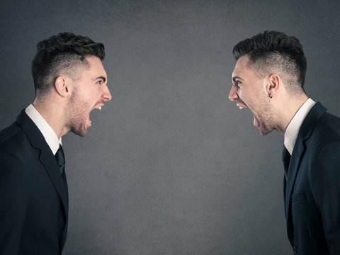 Two angry businessman facing each others. Studio portrait agains