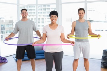Fitness class holding hula hoops around waist in gym - obrazy, fototapety, plakaty