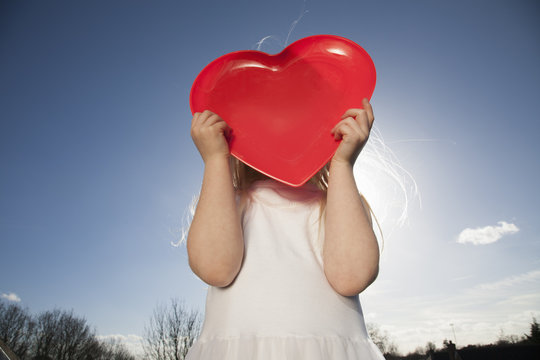 A child holding a red heart shape.