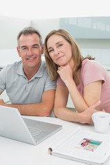 Portrait of a happy couple using laptop in kitchen