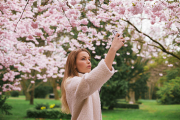Attractive woman photographing flowers at the spring garden