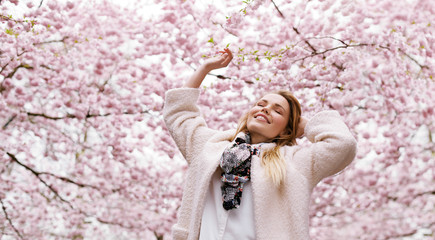 Happy young woman enjoying fresh air at spring blossom park