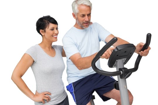 Happy woman looking at mature man on stationary bike
