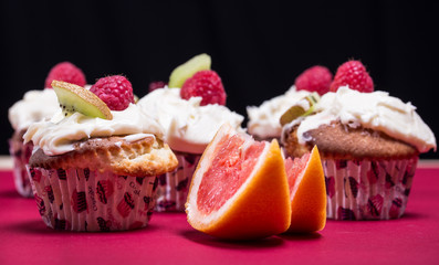 cupcakes with fresh fruits on the red and black background