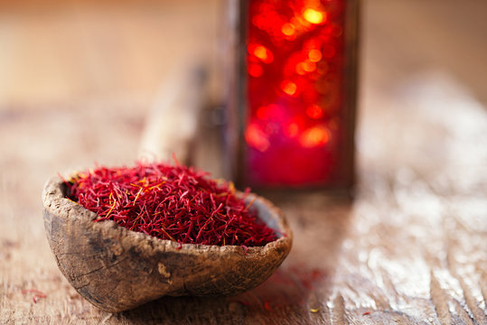 saffron spice in antique wooden spoon on old wood background, cl