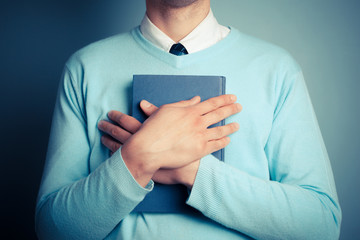 Young man holding a big book
