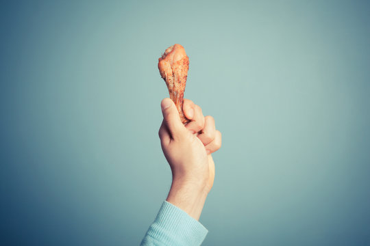 Man holding a chicken drumstick