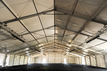 Inside of a huge white tent with rafters