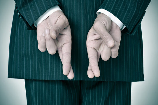 a man wearing a suit crossing his fingers in his back