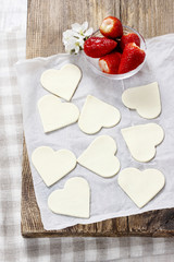 Making puff pastry cookies in heart shape filled with strawberri