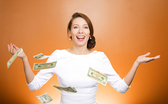 Happy woman throwing money in the air on orange background 