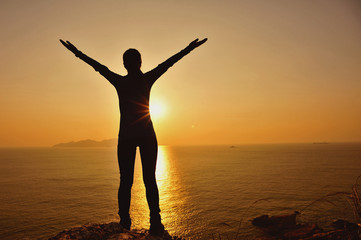 Fototapeta premium cheering woman open arms at sunrise seaside mountain peak