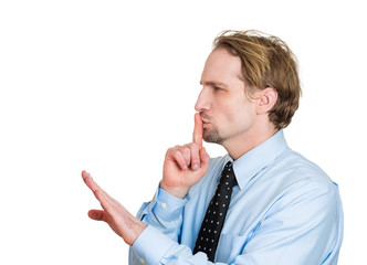Be quiet. Side view man with finger on lips, silence gesture 