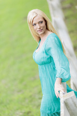 Obraz premium Young blond woman by the fence