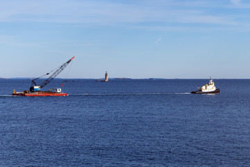 Portland, Maine - Tugboat towing crane in front of lighthouse