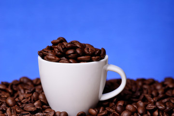 White cup with coffee beans on a blue background