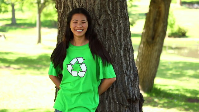 Happy environmental activist leaning against a tree