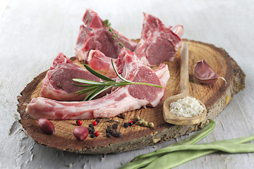 Raw lamb cutlets with rosemary and green been on wooden board