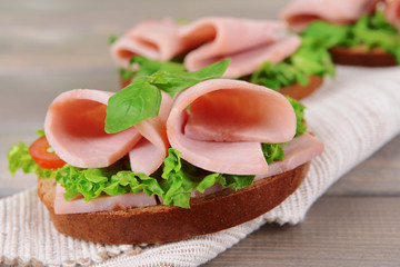 Delicious sandwiches with lettuce and ham on table close-up