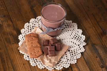 Fototapeta premium Chocolate milk in glass, on wooden table background
