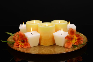Beautiful candles with flowers isolated on black