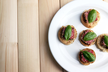 Tasty canapes with salami  and basil leaves,