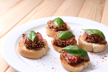 Tasty canapes with salami  and basil leaves,