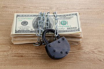 Dollars currency with lock and chain on wooden table