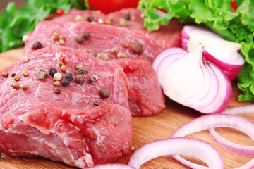 Raw beef meat with vegetables on table close up