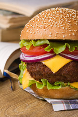 Fresh big hamburger on a background of notebooks and textbooks