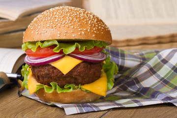 hamburger on a napkin. Background of notebooks and textbooks