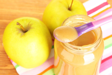 Jar with apple baby food, spoon and apples