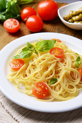 Delicious spaghetti with tomatoes on plate on table close-up
