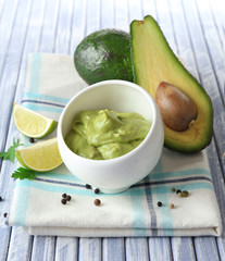 Fresh guacamole in bowl on wooden table