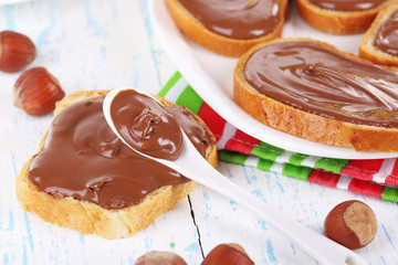 Bread with sweet chocolate hazelnut spread on plate on table