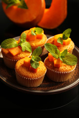 Tasty pumpkin muffins on dark background