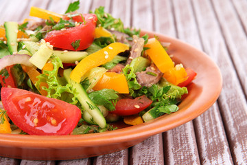 Beef salad on plate on wooden background