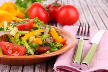 Beef salad on plate with vegetables on wooden background