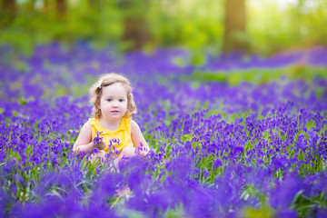 Beautiful toddler girl in bluebell flowers in spring meadow