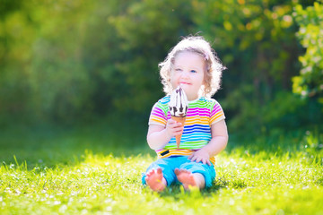 Pretty toddler girl eating ice cream in a sunny garden