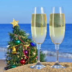 Seascape with glasses of champagne and Christmas tree on the bea