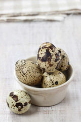 Obraz premium Quail eggs in ceramic bowl standing on rustic wooden table